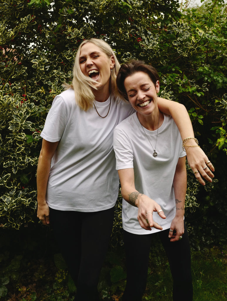 Two women laughing wearing the Evamoso perfect little white tshirt.